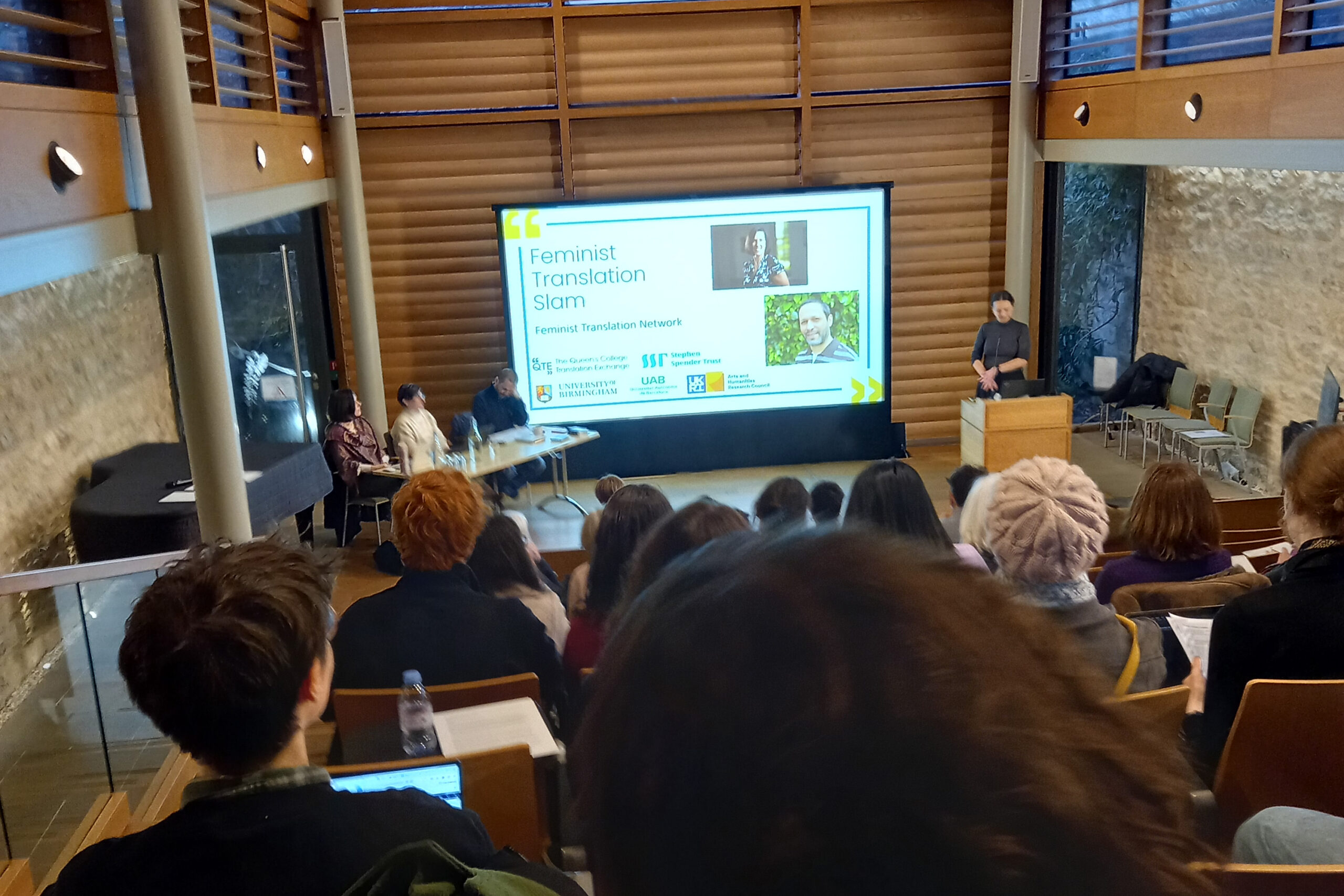 Attendees at Translation slam with Michelle Geoffrion-Vinci and Lawrence Schimel, looking down at the speakers on the stage